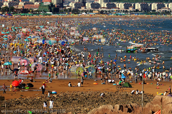 Ba?istas se divierten en Golden Beach (Jinshatan) en Qingdao, una ciudad costera de la provincia de Shandong. Cientos de miles de ba?istas se refrescan en el mar. 17 de agosto de 2014. [Foto/IC]