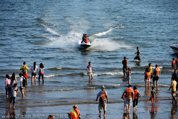 Ba?istas se divierten en Golden Beach (Jinshatan) en Qingdao, una ciudad costera de la provincia de Shandong. Cientos de miles de ba?istas se refrescan en el mar. 17 de agosto de 2014. [Foto/IC]