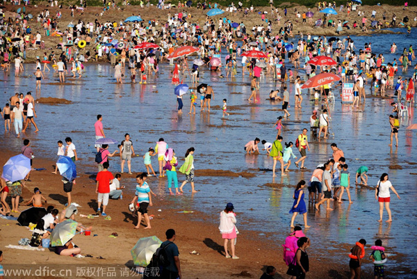 Ba?istas se divierten en Golden Beach (Jinshatan) en Qingdao, una ciudad costera de la provincia de Shandong. Cientos de miles de ba?istas se refrescan en el mar. 17 de agosto de 2014. [Foto/IC]