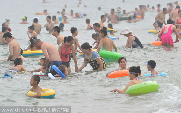 Ba?istas se divierten en una playa de Dalian, en la provincia de Liaoning. Los turistas siguen dispuestos a disfrutar de las playas, aunque el calor del veranose aleja y comienza el principio del oto?o. 17 de agosto de 2014. [Foto/IC] 