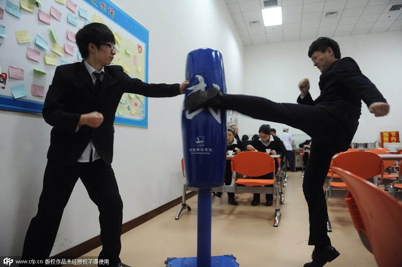 Trabajadores golpean un saco de boxeo en una compa?ía de Pekín, el 7 de enero de 2014. El saco lo instaló la empresa para que los trabajadores alivien su estrés. [Foto / PPC]