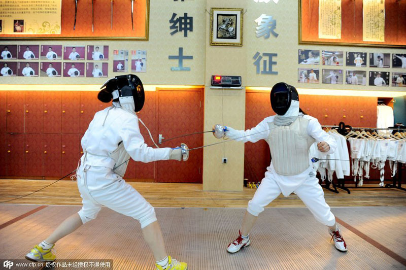 Dos compa?eros de oficina practican esgrima para aliviar el estrés del trabajo, en Shenyang, provincia de Liaoning, el 21 de octubre de 2014. [Foto / PPC]