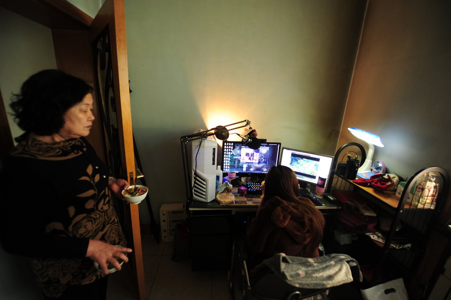 La abuela de Xiaoxue le trae la cena mientras se maquilla en su casa de Taiyuan, capital de la provincia de Shanxi, el 27 de diciembre de 2014. Para estar atractiva, se maquilla siempre antes de ponerse delante de la cámara. [Foto/CFP]