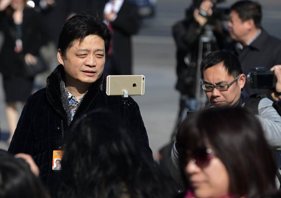 Cui Yongyuan, miembro de la Conferencia Consultiva del Pueblo Chino, hace una selfie con su teléfono móvil antes de entrar a a la sesión anual. Cui, una destacada figura de CCTV, ahora ense?a en la Universidad de Comunicación de China. (Fotografía: Xiaohao)