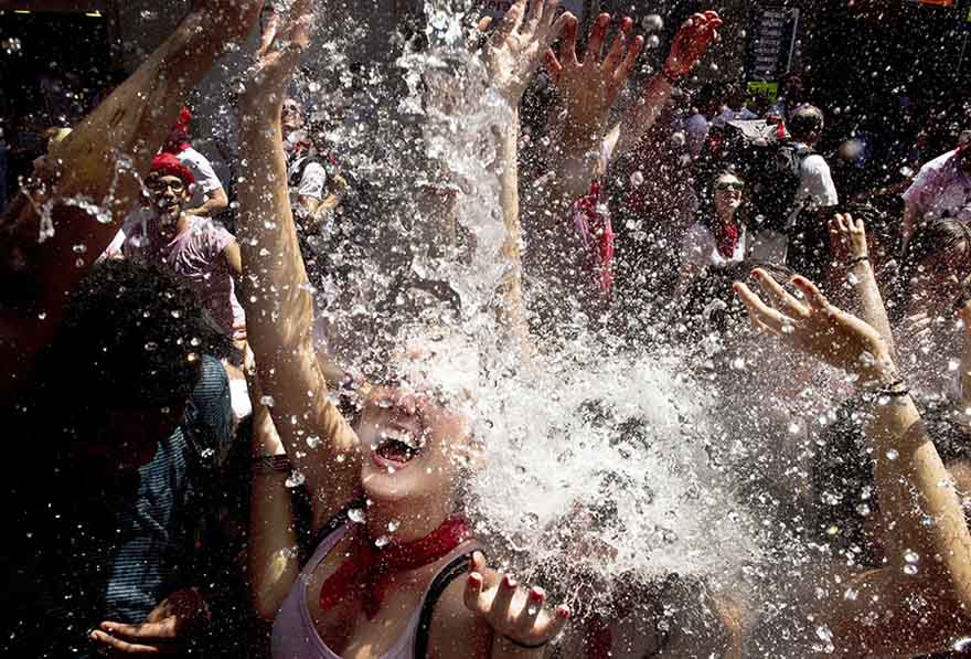 La gente se refresca con agua que los vecinos lanzan desde los balcones durante el inicio de la fiesta de San Fermín en Pamplona, Espa?a, el 6 de julio de 2015. El festival, más conocido por las carreras diarias junto a los toros, arrancó el lunes con el lanzamiento del tradicional "Chupinazo" y durará hasta el 14 de julio. [Agencias de fotografía]