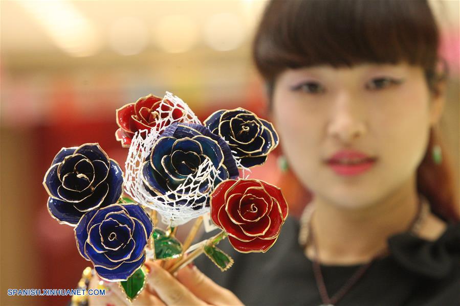 Una empleada muestra rosas doradas en una tienda en la ciudad de Yantai, Shandong provincia, el 12 de febrero de 2016. (Xinhua/Shen Jizhong)