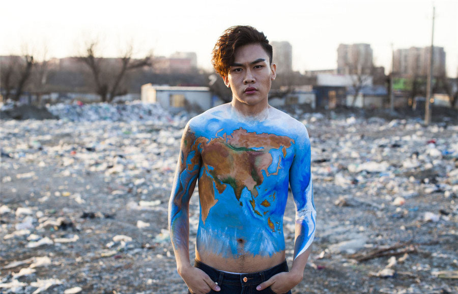 Un modelo con la imagen del planeta pintada en su pecho posa junto a un vertedero de basura el la ciudad de Changchun, capital de la provincia de Jilin, para concienciar sobre la protección del medio ambiente, en vísperas del Día Mundial del Agua.