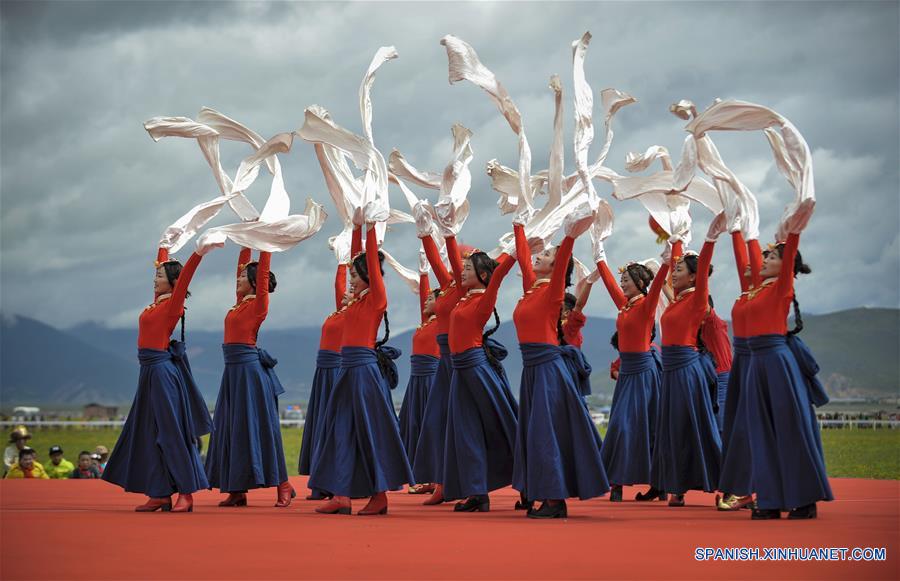 Personas interpretan un baile tradicional durante un festival de carreras de caballos en Shangri-la, Prefectura Autónoma Tibetana de Diqing, en la provincia de Yunnan, en el suroeste de China, el 9 de junio de 2016. Un total de 194 caballos participarán en el festival étnico tradicional de tres días de duración, que dio inicio el jueves. (Xinhua/Zhou Lei)