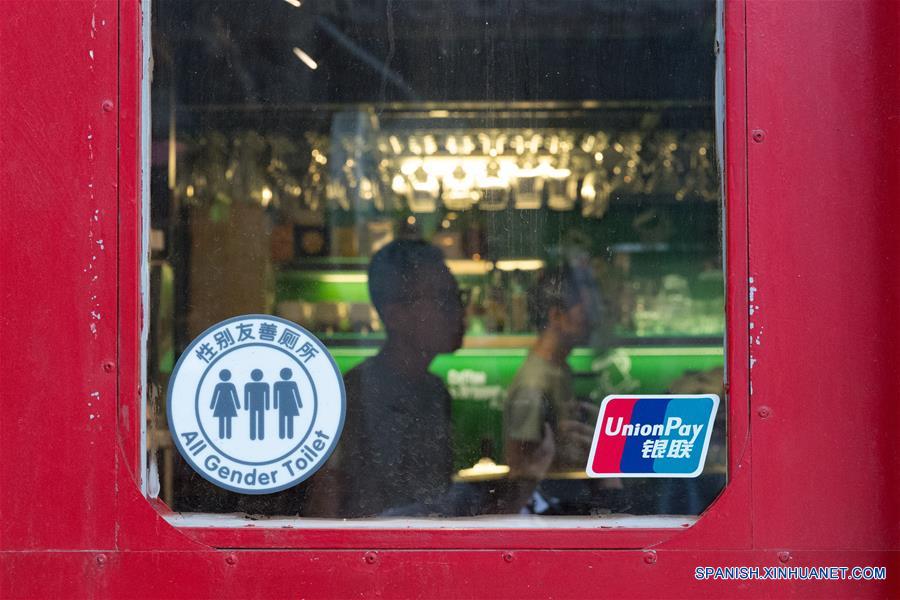 BEIJING, junio 18, 2016 (Xinhua) -- Imagen del 16 de junio de 2016 de un anuncio de "Excusado para Todos los Géneros" captado a la entrada de una cafetería Twin City Cafe en el Callejón de Fangjia en Beijing, capital de China.El Instituto de Educación de Salud de Género de Beijing lanzó el Programa de Excusados para Todos los Géneros en Beijing recientemente con la esperanza de ayudar a público a que ignore las diferencias de género.Los anuncios de Excusados para Todos los Géneros muestra tres figuras: las tradicionales siluetas una portando un vestido, otra con pantalón y se agrega un individuo en un conjunto mitad vestido mitad pantalón. Hay ahora aproximadamente 30 excusados para todos los géneros en cafeterías, bares, y oficinas en toda la ciudad. (Xinhua/Wu Kaixiang)