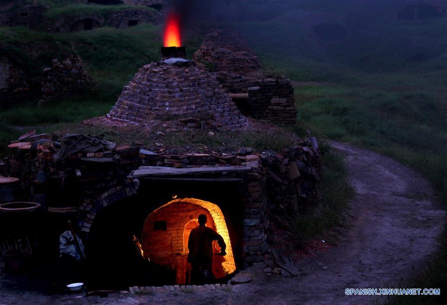 Imagen del 9 de junio de 2016 de un hombre cociendo productos de cerámica, en la zona turística de Yaotou Kiln en el municipio de Yaotou del condado de Chengcheng, provincia de Shaanxi, en el noroeste de China. El sitio de antiguos hornos populares, cubriendo un área de cuatro kilómetros cuadrados, tiene una historia de elaboración de productos de cerámica de más de mil a?os. La técnica de elaboración de cerámica en Yaotou Kiln fue incluida en el Patrimonio Nacional Cultural Intangible en el 2006. (Xinhua/Tao Ming)