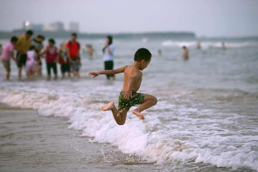 Un ni?o salta al mar en Qionghai de Hainan, el 10 de julio de 2016. [Foto/VCG]