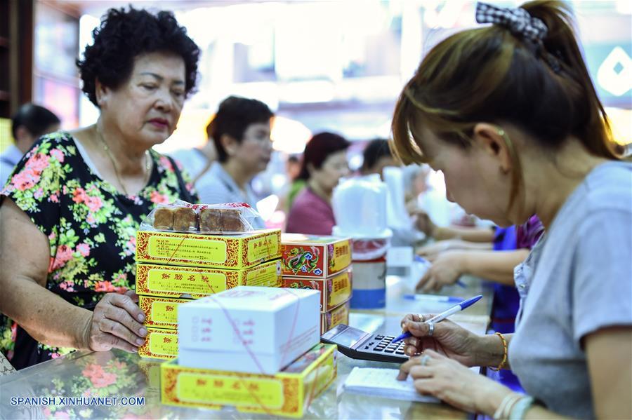 Una empleada (d) calcula el monto total de tartas de luna compradas por clientes previo al Festival de Medio Oto?o en una pastelería en el barrio chino de Bangkok, Tailandia, el 14 de septiembre de 2016. En Tailandia, donde muchos ciudadanos son de origen chino, las personas a menudo adoran a la luna y otras deidades mientras comen tartas de luna junto a los miembros de su familia para celebrar el festival. El Festival de Medio Oto?o cae el 15 de septiembre este a?o. (Xinhua/Li Mangmang)