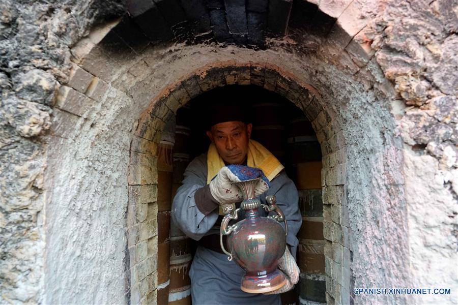 Un miembro del personal saca un artículo Jun de alfarería durante una ceremonia de retiro de porcelanas del horno, en el municipio de Shenhou de la ciudad de Yuzhou, provincia de Henan, en el centro de China, el 19 de noviembre de 2016. La porcelana Jun es famosa por su asobroso cambio de color durante el proceso de fundido en hornos. Shenhou, una localidad antigua ubicada en la zona monta?osa de Henan, tiene una larga historia de elaboración de porcelana Jun. (Xinhua/Li An)