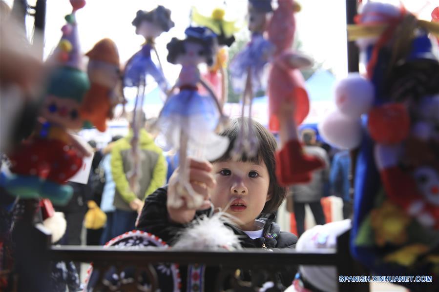 Una ni?a observa las mu?ecas en una feria durante las vacaciones de A?o Nuevo, en Chongqing, en el suroeste de China, el 31 de diciembre de 2016. (Xinhua/Qin Tingfu)