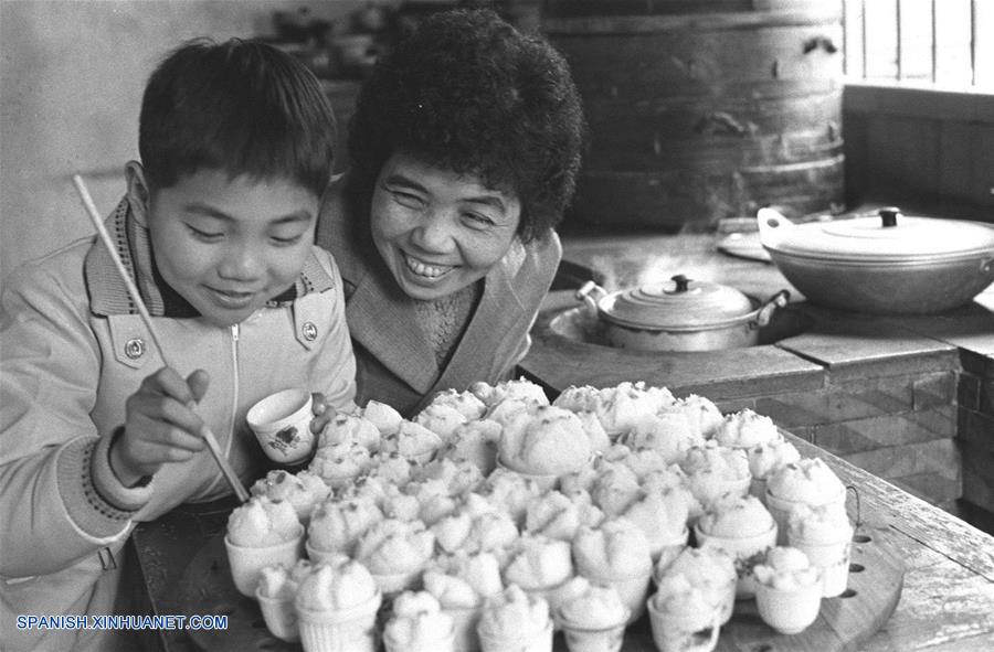  Imagen de archivo tomada en 1980, de Chen Suzhen (d) ense?ando a su hijo a decorar panes al vapor, en la ciudad de Quanzhou de la provincia de Fujian, en el sureste de China. El espíritu más importante del A?o Nuevo Lunar chino, o Festival de Primavera, es la reunión familiar. Es también la mejor época para que las personas de todas las edades se reúnan a disfrutar de una deliciosa comida. (Xinhua/Zheng Zhensun)