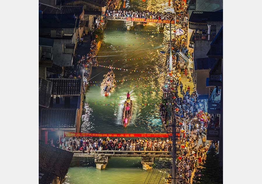 La gente observa la carrera de botes de dragón en una ciudad con río. Foto de Yan Jun. [Foto cedida por photoint.net]