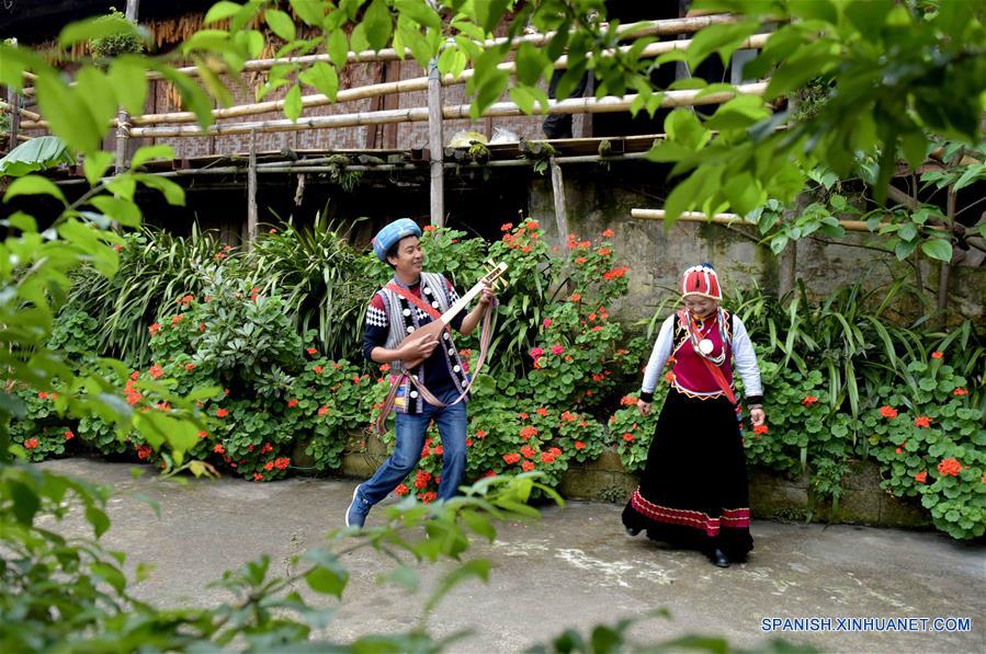 Imagen del 27 de mayo de 2017, de Yu Wulin (i) y su esposa Lu Binghua (d) cantando y bailando en su estancia familiar en el poblado de Laomudeng en el municipio étnico de Pihe Nu, en la provincia de Yunnan, en el suroeste de China. En 1996, Yu Wulin fue elegido para promover la cultura del grupo étnico Nu en Shanghai y se enamoró de la bailarina Lu Binghua. Después de regresar a su ciudad natal, se casaron y abrieron una estancia familiar para turistas. Crearon una marca de té y vendieron sus productos locales de té a mercados extranjeros. Gracias a la inspiración de la pareja, muchos residentes locales abrieron estancias familiares, y la vida ha cambiado en el poblado remoto. (Xinhua/Yang Zongyou)