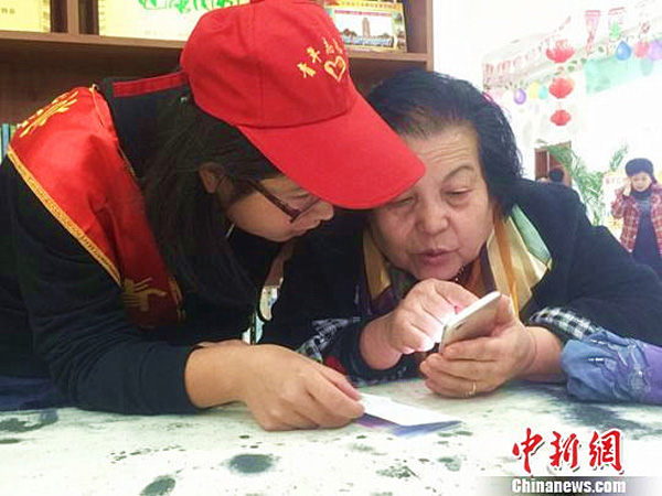 Un voluntario ense?a a una persona de la tercera edad a usar wechat en Lanzhou, provincia de Gansu, 25 de octubre del 2017. [Foto: chinnews.com]