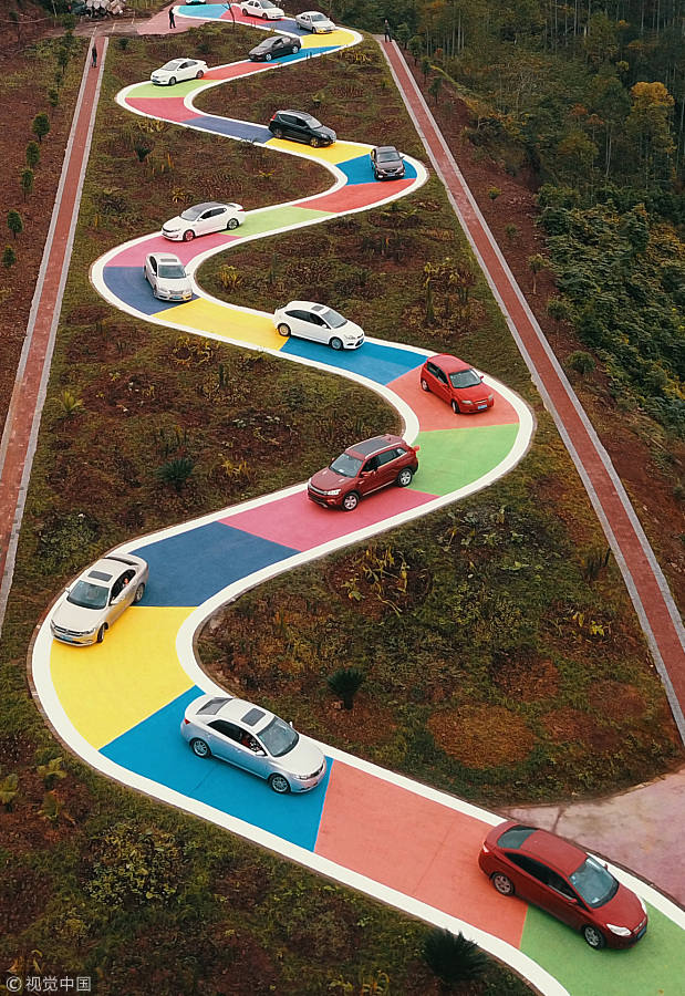 El 18 de noviembre de 2017, varios vehículos circulan por una carretera en forma de serpiente en Chongqing, sudoeste de China. La calle de 185 metros con superficie colorida entró en funcionamiento como lugar de ocio. [Foto / VCG]