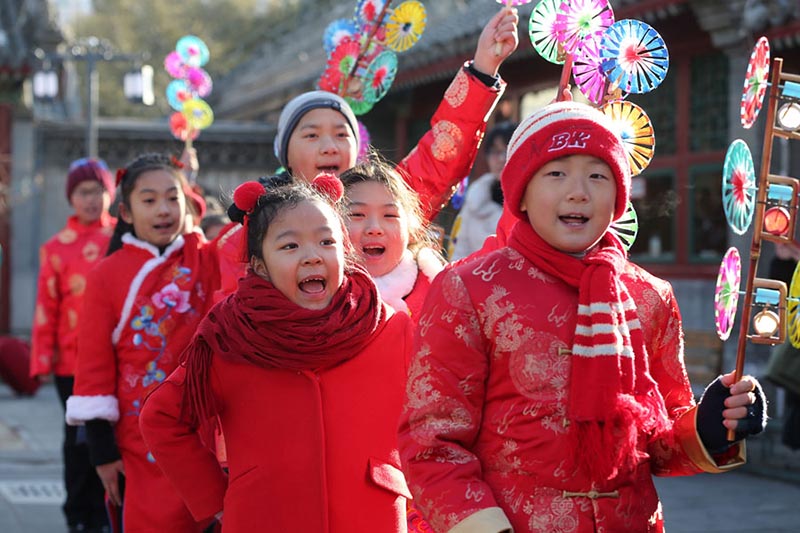 Los ni?os con trajes festivos de colores juegan con molinetes de colores en el Observatorio Antiguo en Beijing para celebrar el periodo del calendario lunar Comienzo de la Primavera, que comenzó el domingo. [Foto de Wang Zhuangfei / chinadaily.com.cn]