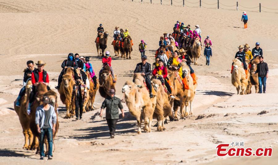 Los turistas visitan las monta?as arenosas cantantes de Dunhuang 