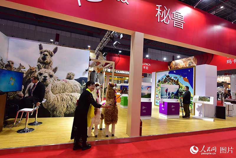 El 5 de noviembre, una visitante se hace fotos con las alpacas en el pabellón de Perú. Foto de Weng Qiyu, Pueblo en Línea)