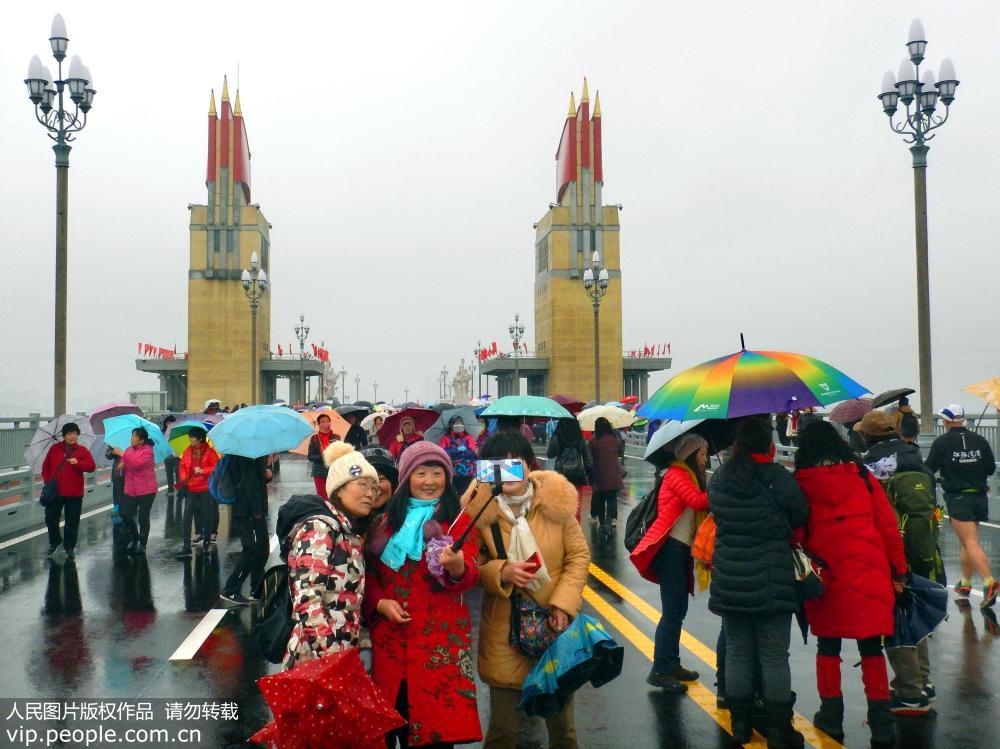 La gente en Nanjing desafía a la lluvia cruzando el recién renovado puente sobre el río Yangtse