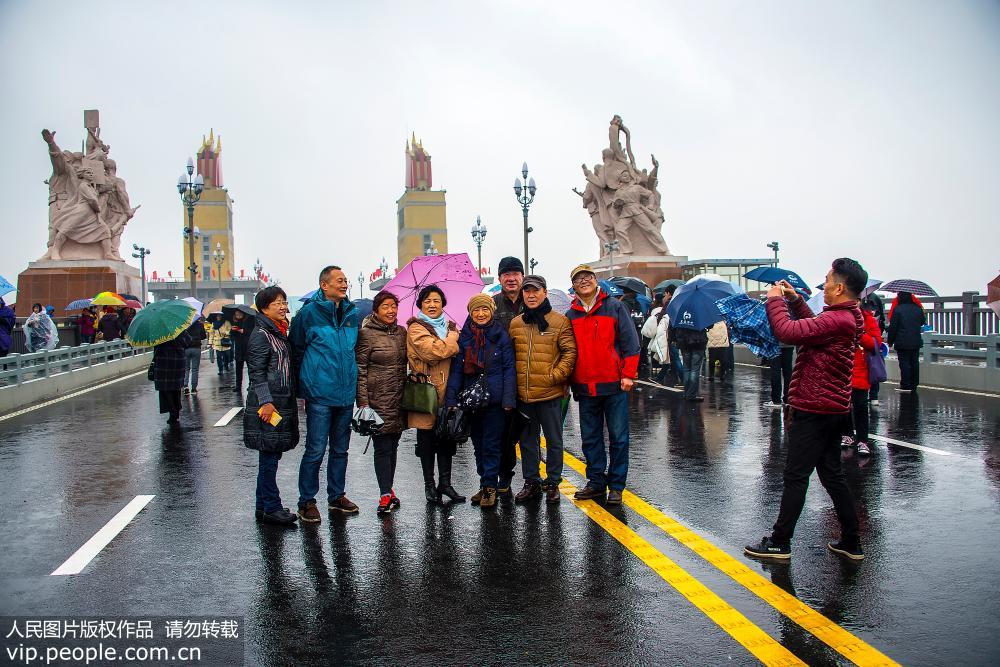 La gente en Nanjing desafía a la lluvia cruzando el recién renovado puente sobre el río Yangtse