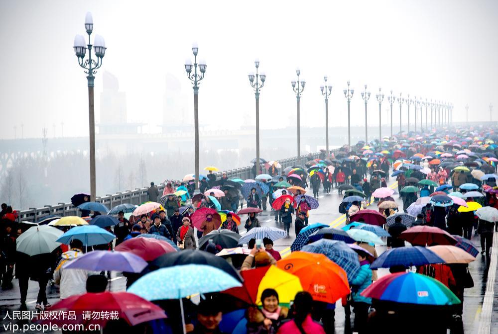 La gente en Nanjing desafía a la lluvia cruzando el recién renovado puente sobre el río Yangtse