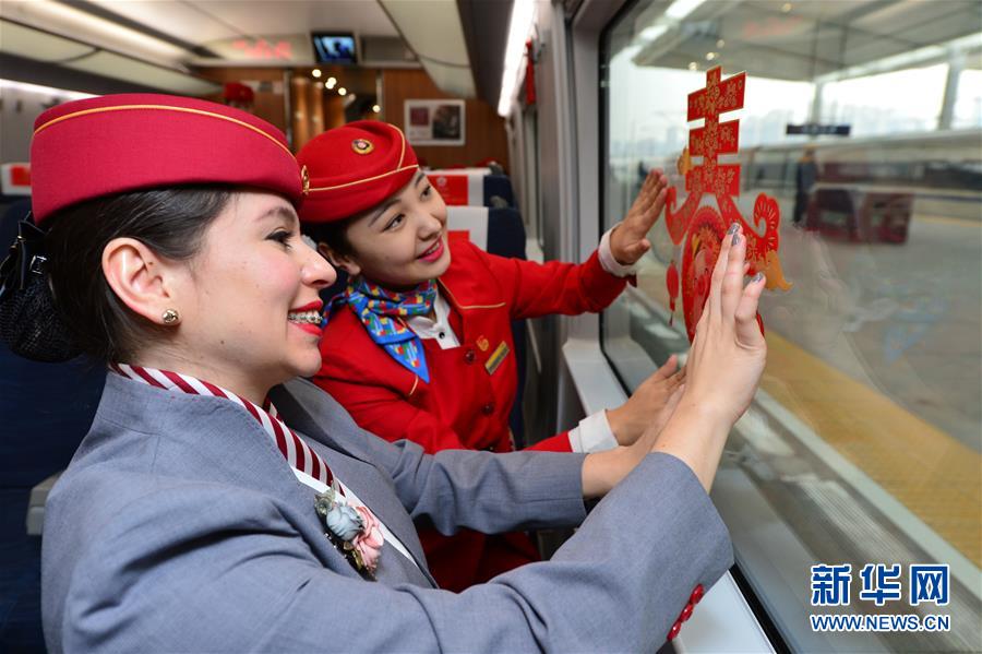 El 20 de enero, en un tren de alta velocidad de la estación ferroviaria Xi'an Norte, una estudiante voluntaria extranjera (izquierda) decora los vagones junto con una azafata.