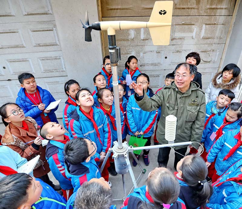 La gente de la comunidad de Gongrenbeili y los estudiantes de la Escuela Primaria Hedong, distrito de la ciudad de Qinhuangdao, provincia de Hebei, norte de China, aprenden el principio de funcionamiento de una estación meteorológica automática, el 22 marzo 2018. (Cao Jianxiong / Diario del Pueblo)