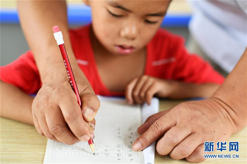 Wu Guoxian ense?a a un estudiante a escribir pinyin en la Escuela Primaria Gugang, el 27 de agosto de 2019. [Foto / Xinhua]