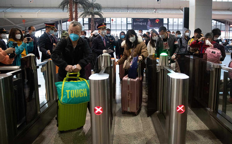 Después de medir su temperatura, los pasajeros entran en la estación de trenes de Wuhan. [Foto: Ke Hao/China Daily] 