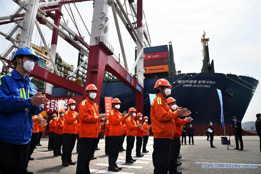 Trabajadores participan en la ceremonia realizada por el viaje inaugural del buque HMM Algeciras, en el puerto de Qingdao, en Qingdao, provincia de Shandong, en el este de China, el 26 de abril de 2020. El HMM Algeciras, el buque portacontenedores más grande del mundo con una capacidad de 24.000 TEU (unidad equivalente a 20 pies), comenzó el domingo su primer viaje desde el puerto de Qingdao. (Xinhua/Li Ziheng)