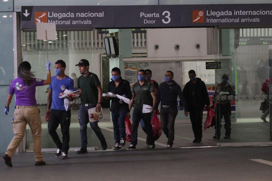 Una trabajadora del Instituto Nacional de Migración guía, el 22 de mayo de 2020 en el Aeropuerto Internacional de la Ciudad de México, en la capital mexicana, a un grupo de mexicanos deportados desde Estados Unidos a los vehículos que los transportarán a las diferentes centrales camioneras desde donde viajarán a sus destinos. (Xinhua/Francisco Ca?edo)