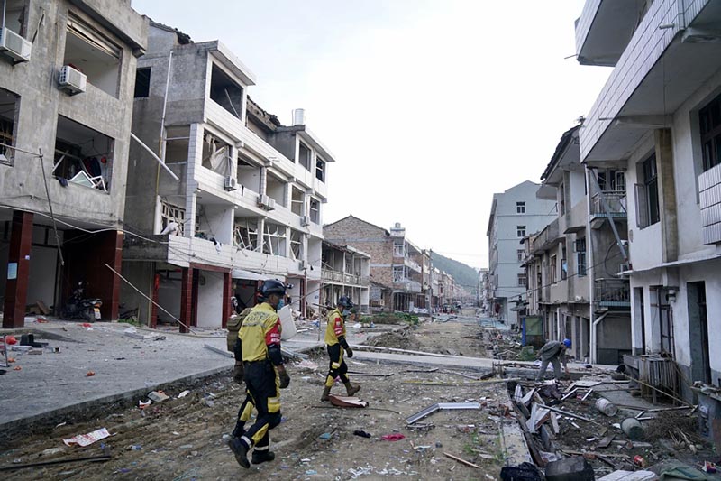 Miembros del equipo de rescate entran en un edificio da?ado en el lugar de la explosión de un camión en Zhejiang. [Foto proporcionada a China Daily]