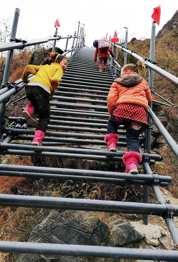 Los ni?os están subiendo las escaleras de acero de la "aldea del acantilado" bajo la guía de los padres en un proyecto de turismo cultural en enero de 2018. Esta actividad no solo puede garantizar la seguridad, sino también aumentar el coraje de los ni?os. (Foto: Rao Guojun/ Pueblo en Línea)