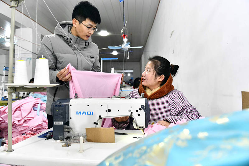 Hu Chunqing se comunica con una trabajadora de su taller. [Foto: Xinhua]