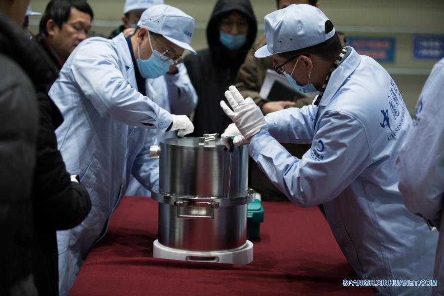 Imagen del 17 de diciembre de 2020 de investigadores científicos transfiriendo el contenedor cargado con muestras lunares obtenidas por la sonda espacial Chang'e-5, en Beijing, capital de China. La sonda espacial Chang'e-5 de China trajo a la Tierra alrededor de 1.731 gramos de muestras tomadas en la Luna, según informó la Administración Nacional del Espacio de China. Los científicos llevarán a cabo el almacenamiento, análisis e investigación de las primeras muestras lunares recolectadas por China. (Xinhua/Jin Liwang)