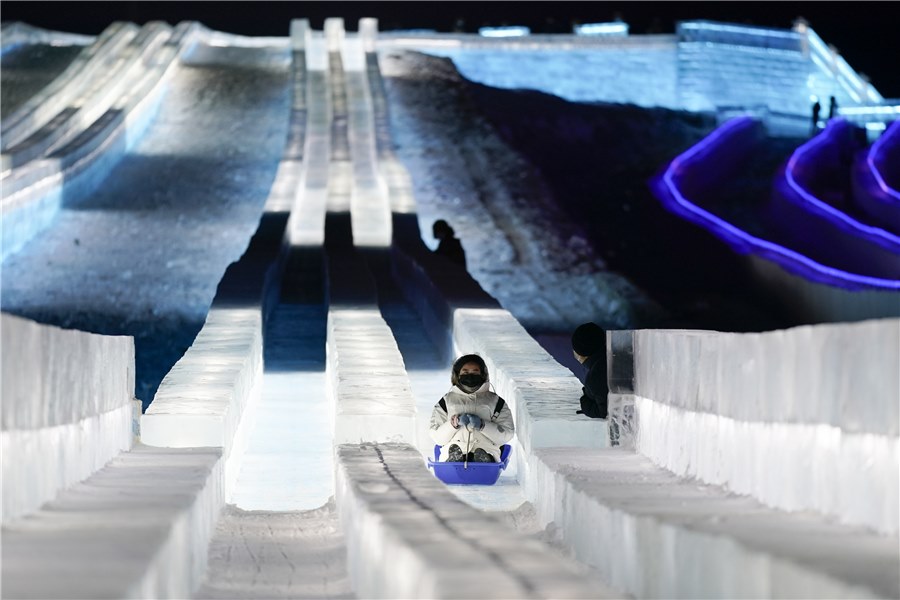 Un turista se divierte en un tobogán de hielo durante el inicio de la XXII edición del Mundo de la Nieve y el Hielo en Harbin, provincia de Heilongjiang, 24 de diciembre de 2020. [Foto: Lyu Pin/ China Daily]