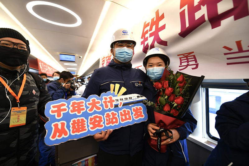 Una pareja que participó en la construcción del ferrocarril interurbano Beijing-Xiong'an se hacen fotos a bordo del primer ferrocarril que une Beijing y la Nueva área de Xiong′an, en la Estación de Ferrocarriles Oeste de Beijing, el 27 de diciembre de 2020. [Foto de Sun Lijun / chinadaily.com.cn]