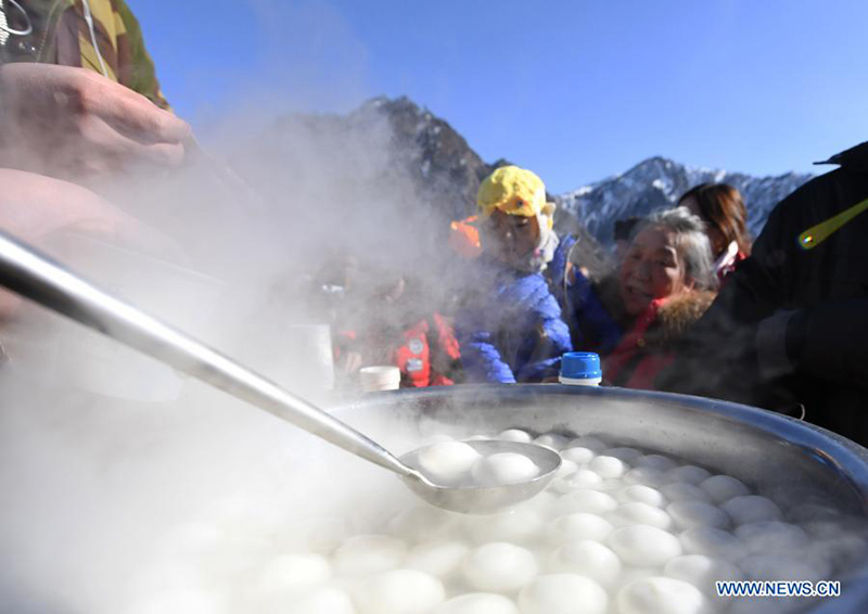 Los turistas piden Yuanxiao, bolas de harina de arroz glutinoso hervido que normalmente se consumen al final de las vacaciones del A?o Nuevo Chino, en el Parque Nacional Tianchi de Tianshan en la región autónoma Uygur de Xinjiang, en el noroeste de China, el 17 de febrero de 2021. [Foto / Xinhua]