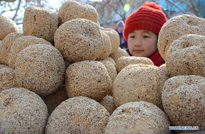 Un ni?o compra "melón de azúcar", un aperitivo de A?o Nuevo Chino hecho de azúcar de malta, arroz glutinoso y sésamo, en el condado Yiyuan de la provincia de Shandong, en el este de China, el 10 de febrero de 2015. [Foto / Xinhua]