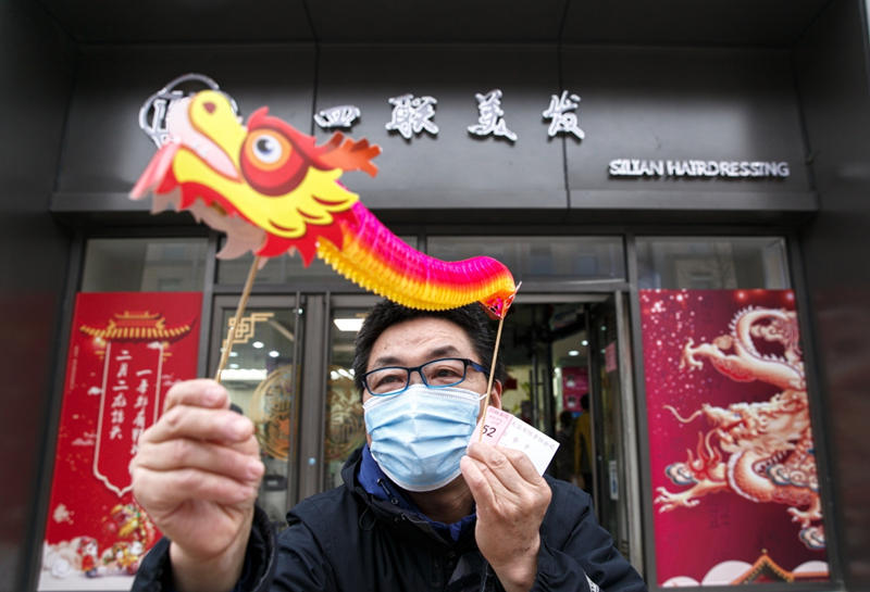 Un residente en la capital china recibe un dragón en la barbería-peluquería Silian, ubicada en la atractiva calle de Wangfujing, hoy tuvo que “madrugar” para atender a la mayor cantidad de clientes diarios del a?o, Beijing, 14 de marzo del 2021. [Foto: Jiang Dong/ China Daily]