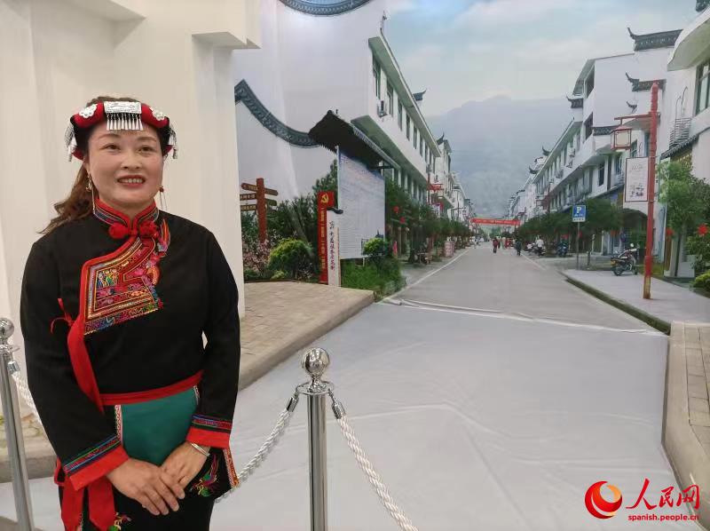 Zong Limei, esposa y madre afectada por la pobreza, posa en el Memorial de la Ruta hacia la Erradicación de la Pobreza junto a una fotografía de su nuevo barrio en Ningde, Fujian, 25 de mayo del 2021. (Foto: YAC/ Pueblo en Línea)