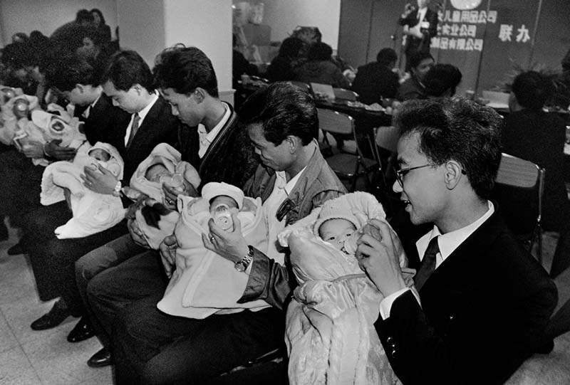 Padres alimentan a sus bebés en un centro comercial de Guangzhou, provincia de Guangdong, 1993. (Foto: Ye Jianqiang)  