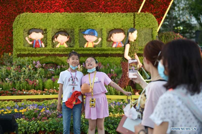 Ni?os posan junto a decoraciones florales que embellece la capitalina avenida Chang'an, 19 de junio del 2021. [Foto: Xinhua]