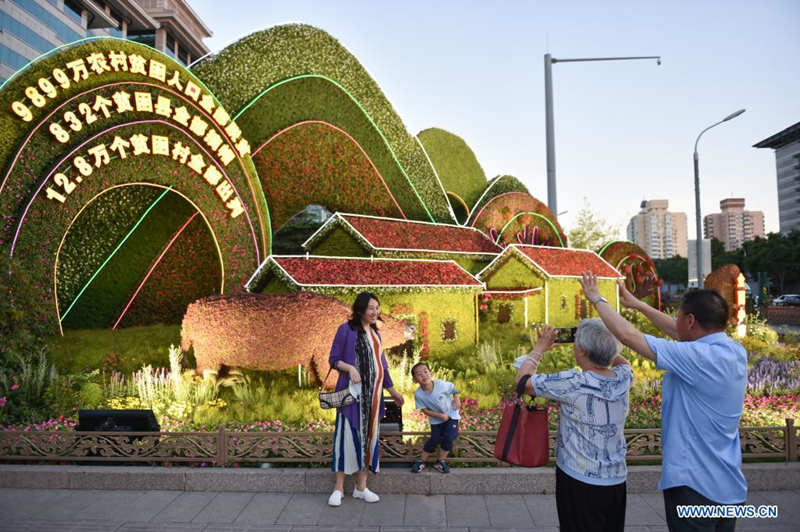 Personas posan junto a decoraciones florales que embellece la capitalina avenida Chang'an, 19 de junio del 2021. [Foto: Xinhua]