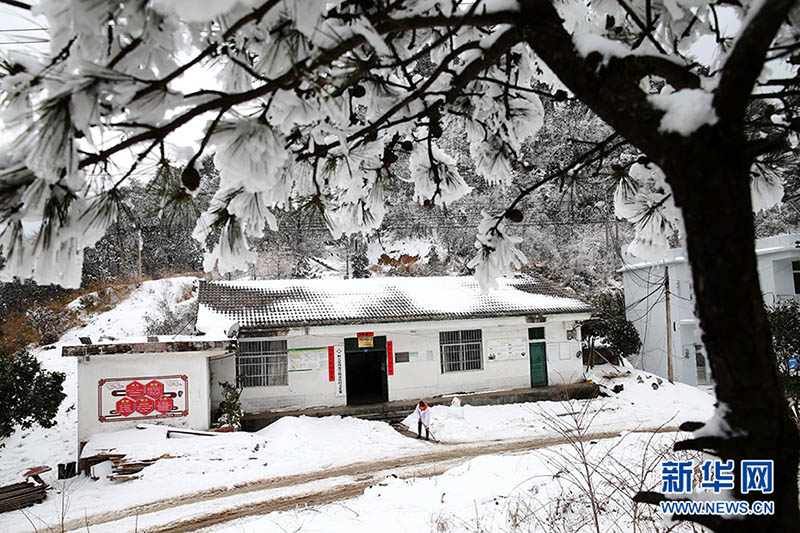 Shuai Xiaoyun barre la nieve que bloquea la entrada principal del consultorio de la aldea pueblo, 10 de febrero de 2022 [Foto: Xinhua]