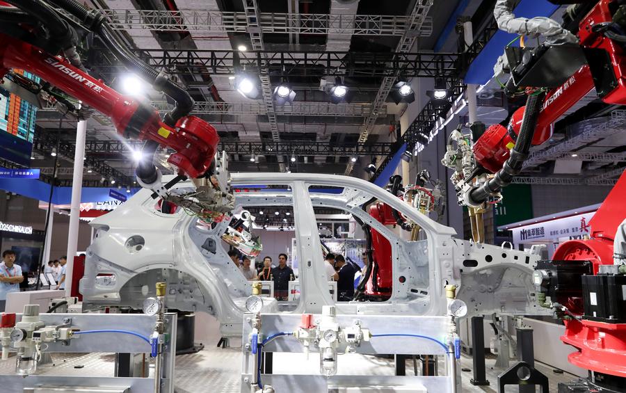 Visitantes observan a un robot soldar una carrocería de automóvil durante la 23a Feria Internacional de la Industria de China (CIIF, por sus siglas en inglés), en Shanghai, en el este de China, el 19 de septiembre de 2023. (Xinhua/Fang Zhe)